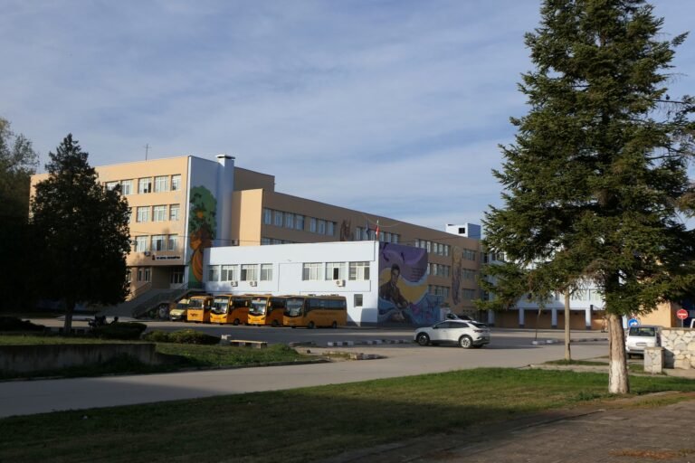 School building and buses in Strazhitsa, Bulgaria — archival photograph, not from the procession
