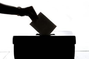 Voter casting a ballot into a ballot box; illustrative election-day photo